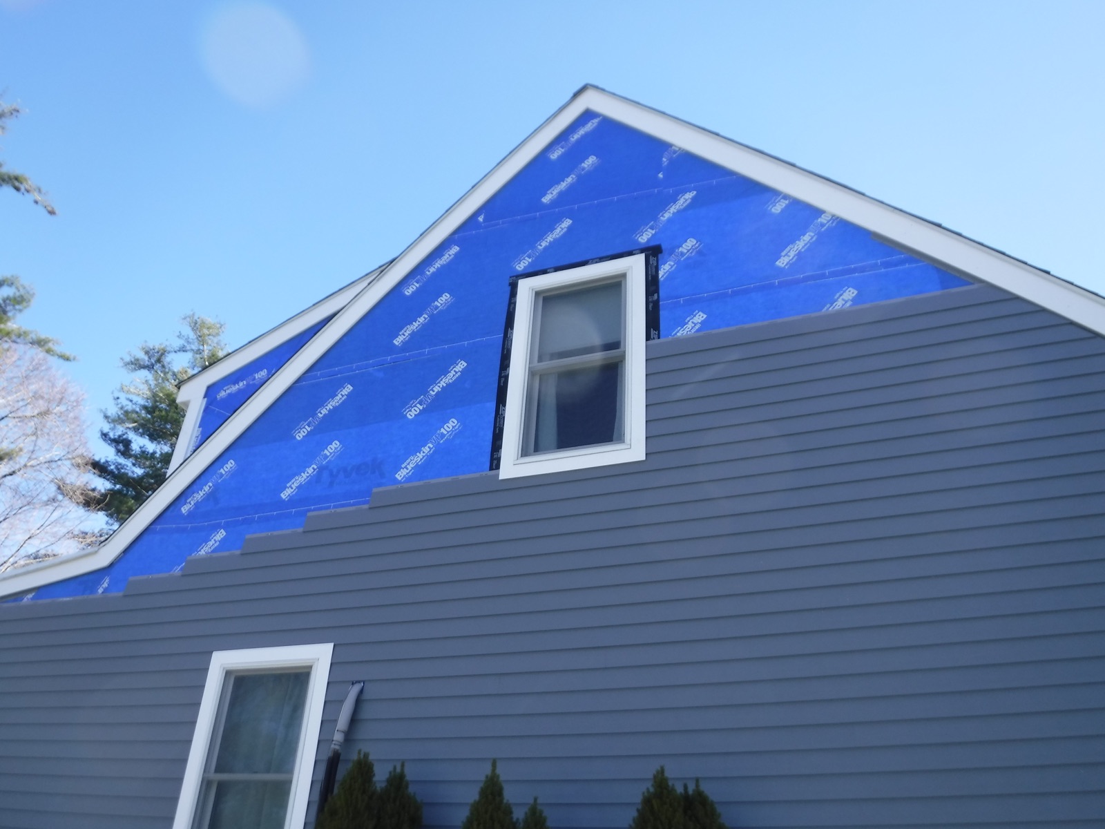 Exterior home renovation in progress in Massachusetts with new siding and weather barrier